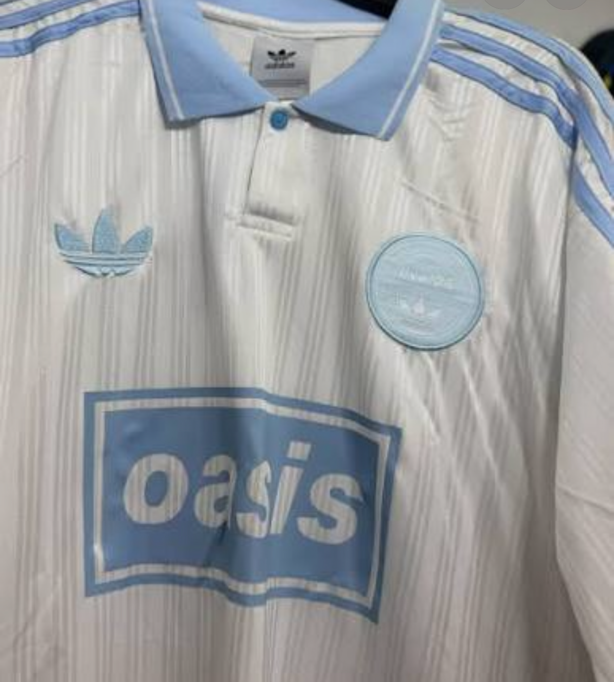 Adidas Oasis Tour "Bolt Makers Arms" short sleeve soccer jersey in white and sky blue, featuring retro World Cup design.