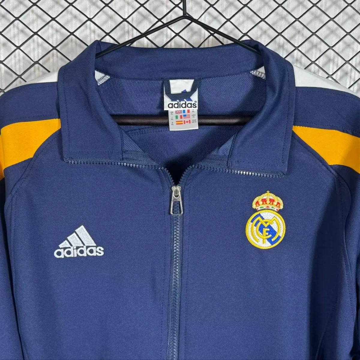 Real Madrid 98/99 Track Retro long sleeve jacket with team logo and vintage design, worn by a person in a casual setting.