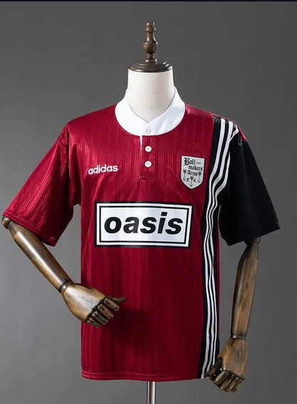 Red and black Adidas Oasis Tour “Bolt Makers Arms” edition short sleeve soccer jersey featuring bold design and team branding.