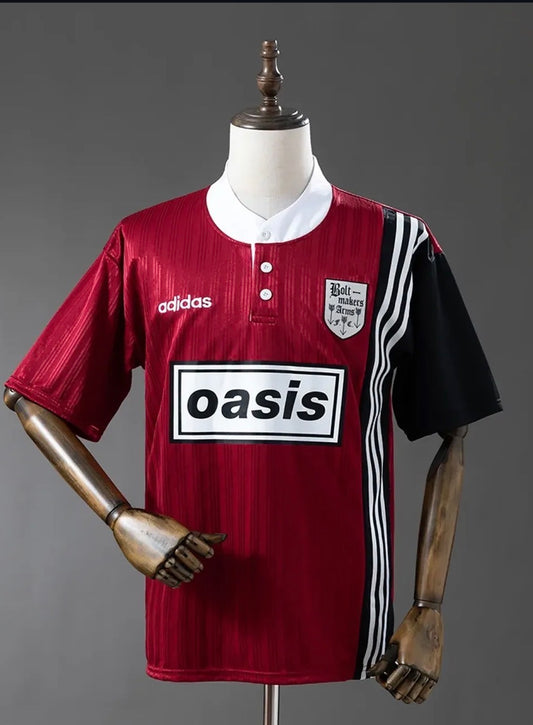 Red and black Adidas Oasis Tour “Bolt Makers Arms” edition short sleeve soccer jersey featuring bold design and team branding.