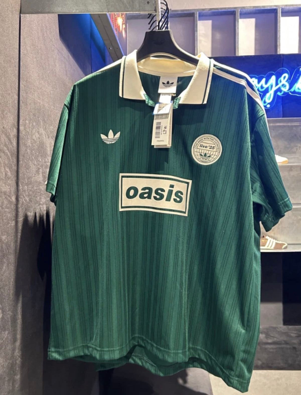 Green Adidas OASIS TOUR Lifestyle short sleeve soccer kit with team logo and design details, perfect for casual sportswear.